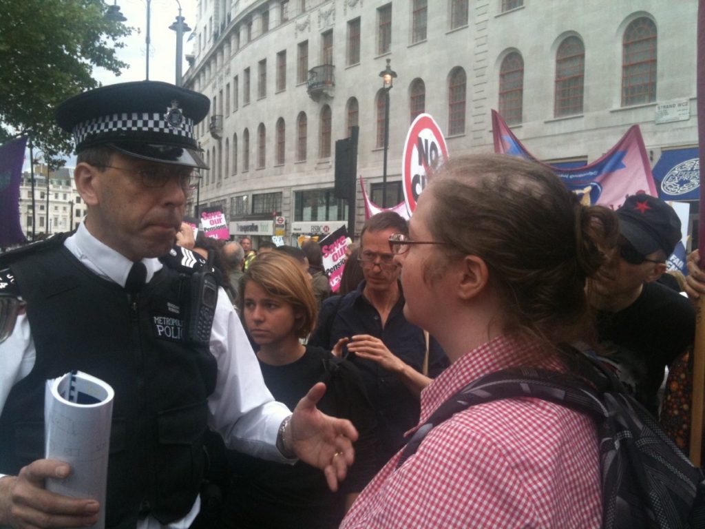 A policeman negotiates with a teacher at a protest for public sector pensions 