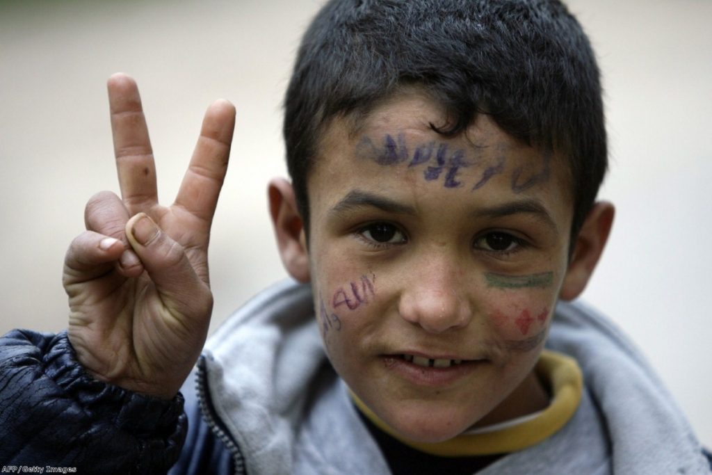 A young Syrian refugee who fled  the violence in Homs flashes the 'V for victory' sign as he takes shelter in northern Lebanon