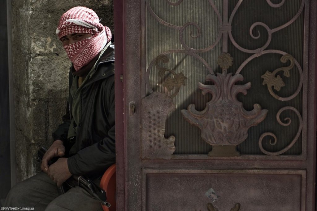 A Free Syria Army member sits guard during the funeral of a man near Homs this week.