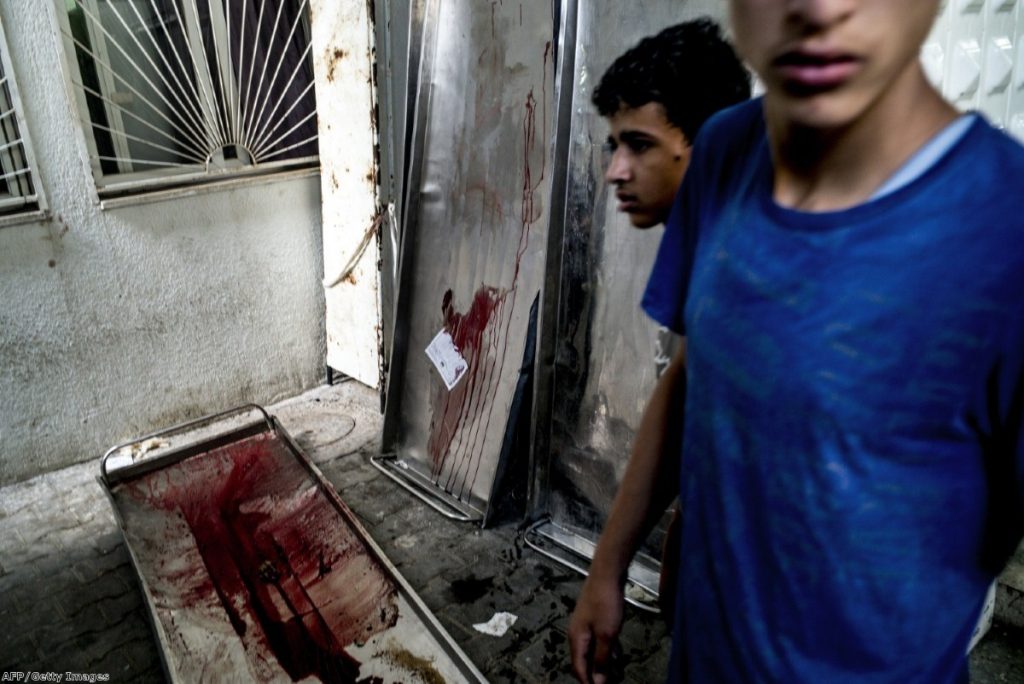 Blood-stained gurneys are seen outside the morgue at the Kamal Adwan hospital in Beit Lahia, as members of the Abu Nejim family gather to collect their family members killed in an airstrike on their house on Monday