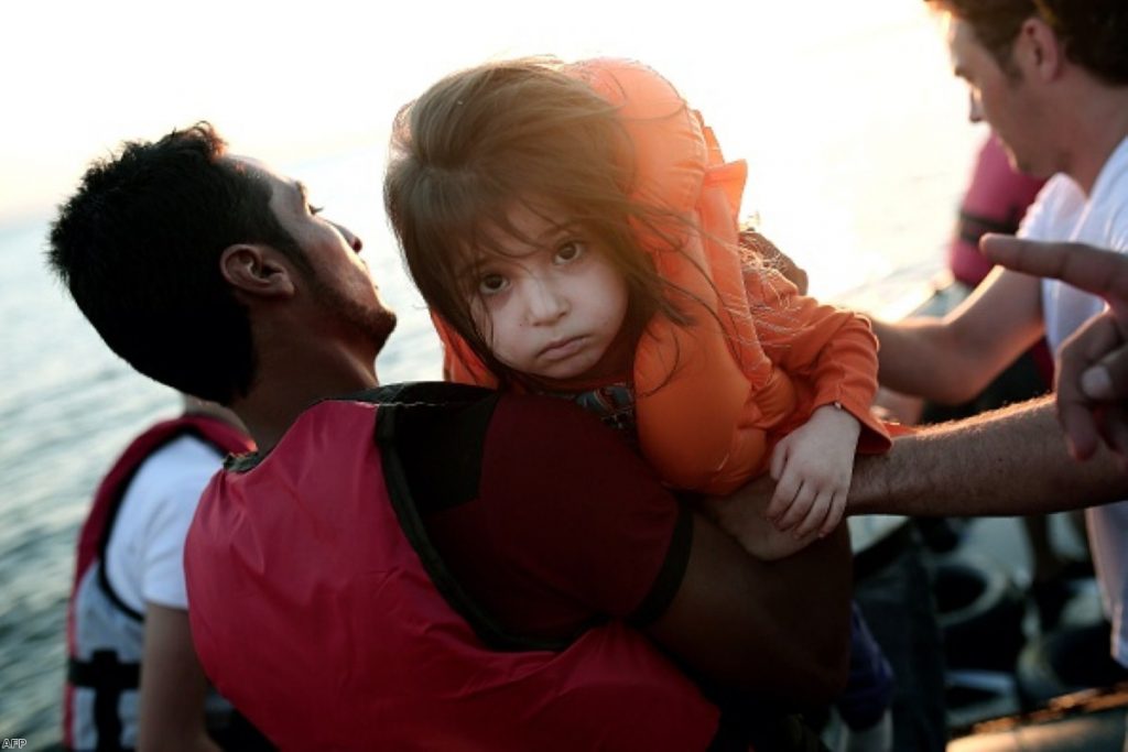 Girl carried out of an inflatable boat on the Greek island of Kos after crossing the Aegean Sea   