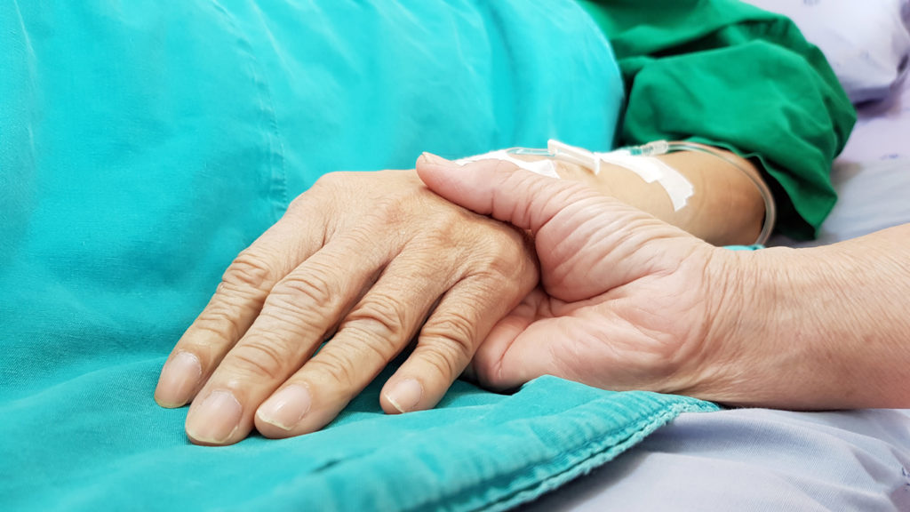 Oncologist doctor holding patient's hand in hospital. Showing all love, empathy, helping and encouragement. He has end stage cancer disease. Healthcare in end of life and palliative care concept