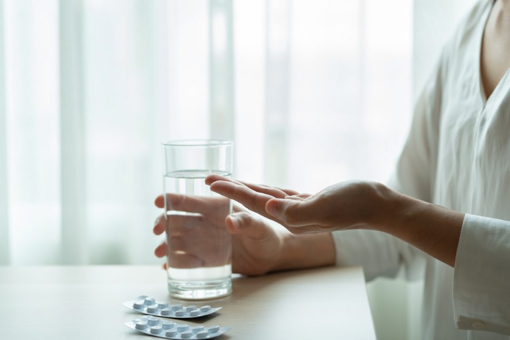 Woman holds medicine with a glass of water, healthcare and medicine recovery concept